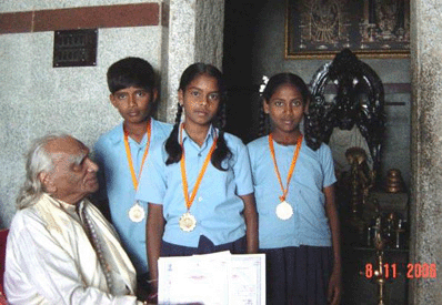 3 students being given medals and certificates by BKS Iyengar